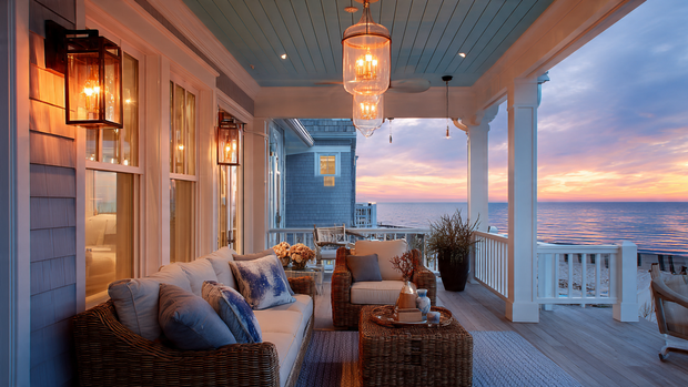 Cozy coastal porch with lantern lighting and wicker chairs in warm evening light.