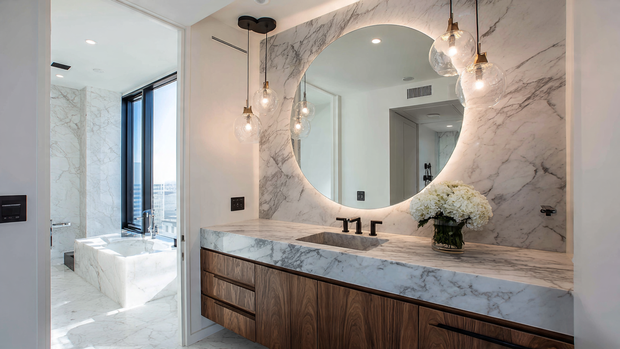 16 Luxurious Bathroom Design Ideas for a Spa-Like Retreat 12 Spacious bathroom with a large illuminated mirror and marble vanity.