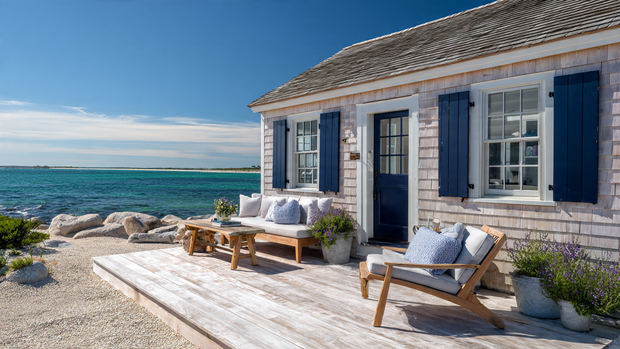 Modern coastal cottage with shiplap siding and navy shutters near the beach.