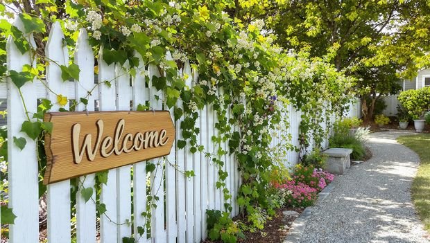 16 Timeless Cottage Decor Ideas to Warm Up Your Space 13 White picket fence with a wooden welcome sign and climbing plants.
