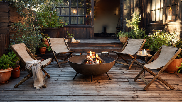 16 Cozy and Modern Backyard Fire Pit Ideas 8 Portable metal fire bowl on deck with chairs and plants.