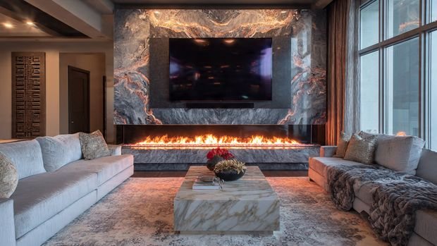 Modern living room with fireplace and TV combo wall featuring marble cladding and ambient lighting